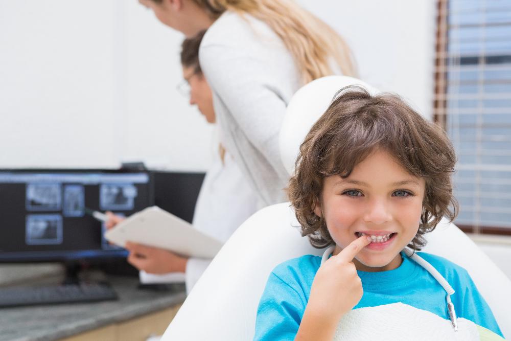 young boy touching mouth in exam chair | orthodontics harris park