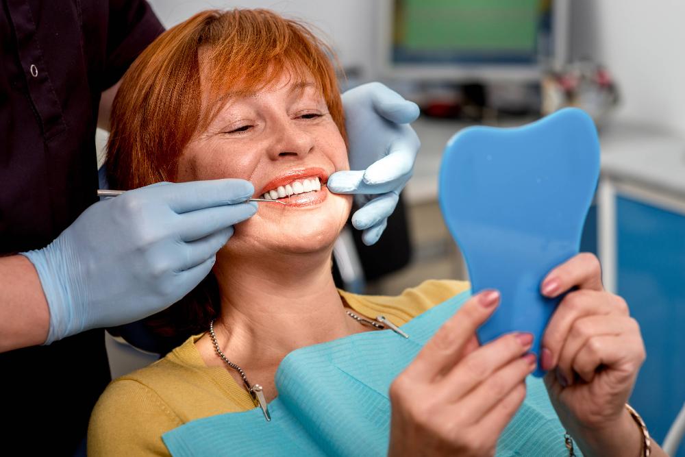 woman smiling in mirror in exam chair | orthodontics harris park