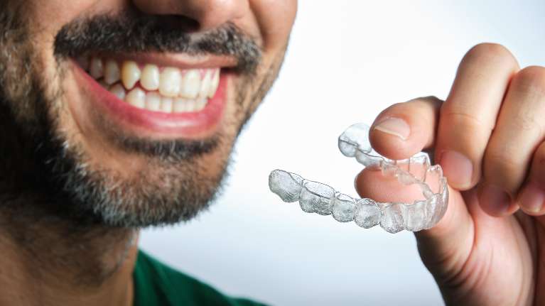 an orthodontic patient holding his Invisalign Express aligners